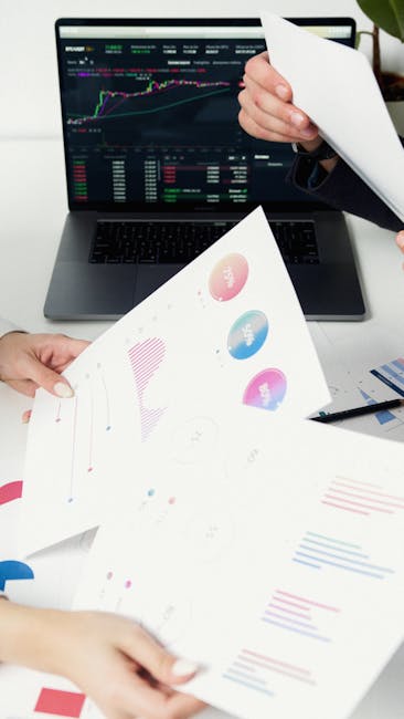 Equipo de trabajo colaborando alrededor de una mesa con portátiles y documentos